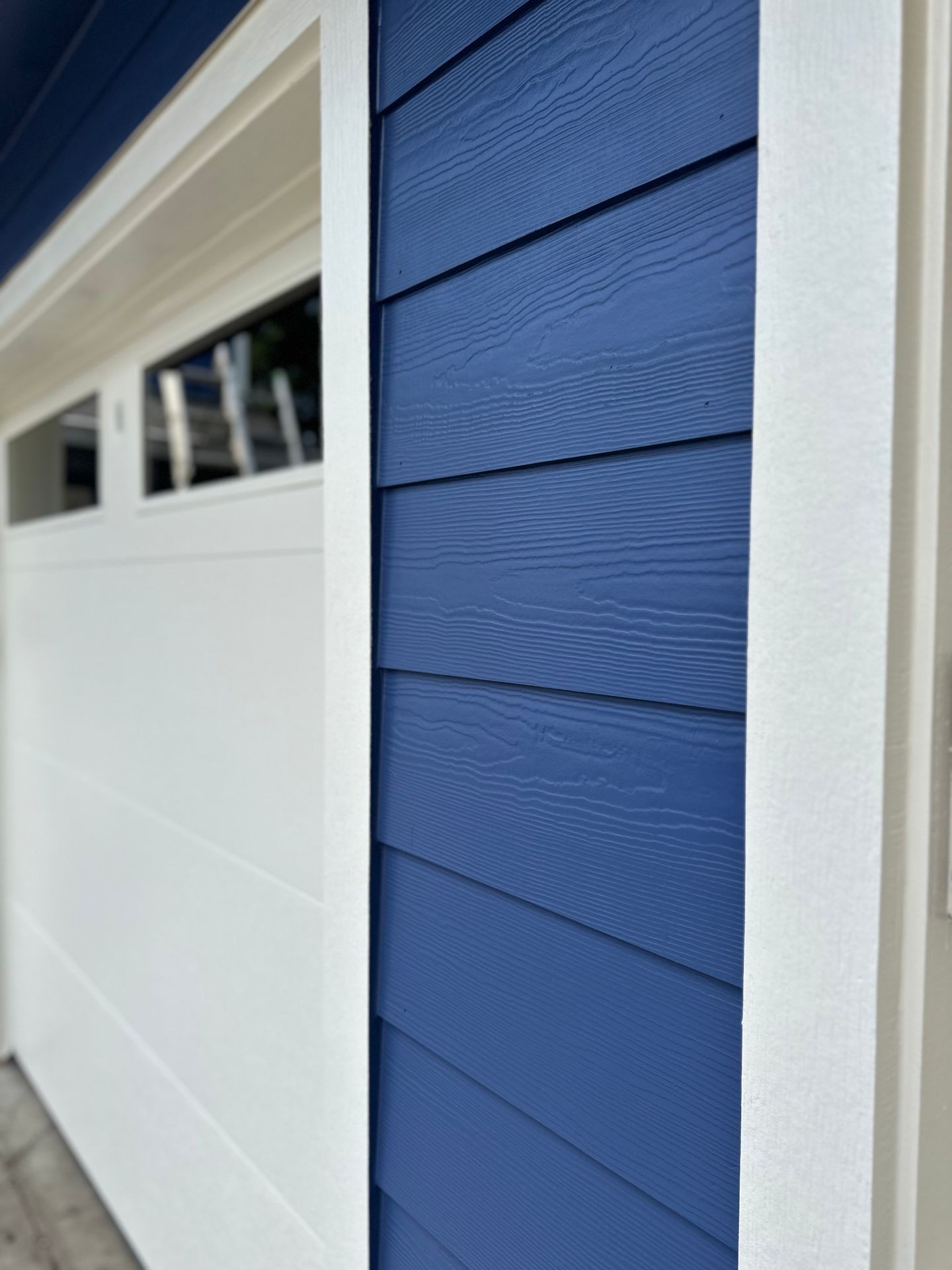 Close-up of a blue and white exterior wall with horizontal siding near a garage door.